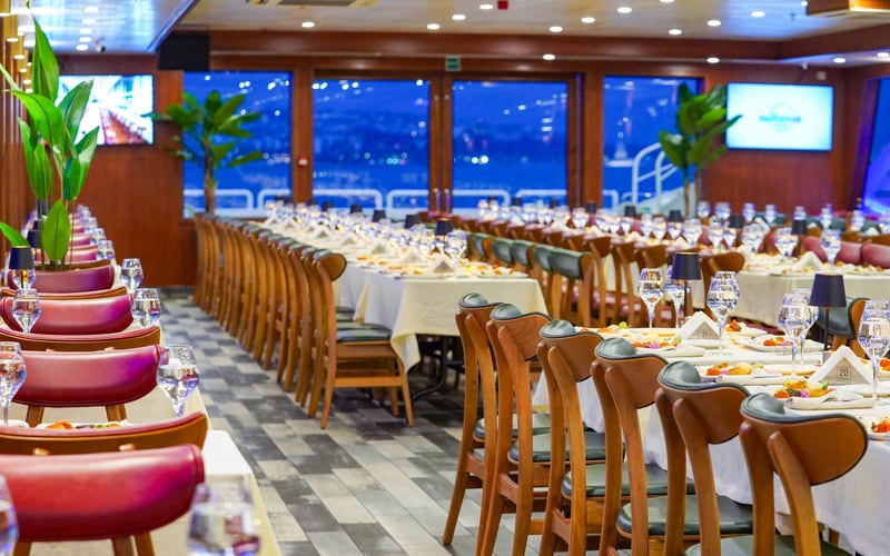 The enclosed dining salon on our Bosphorus dinner cruise with laid tables and panoramic windows