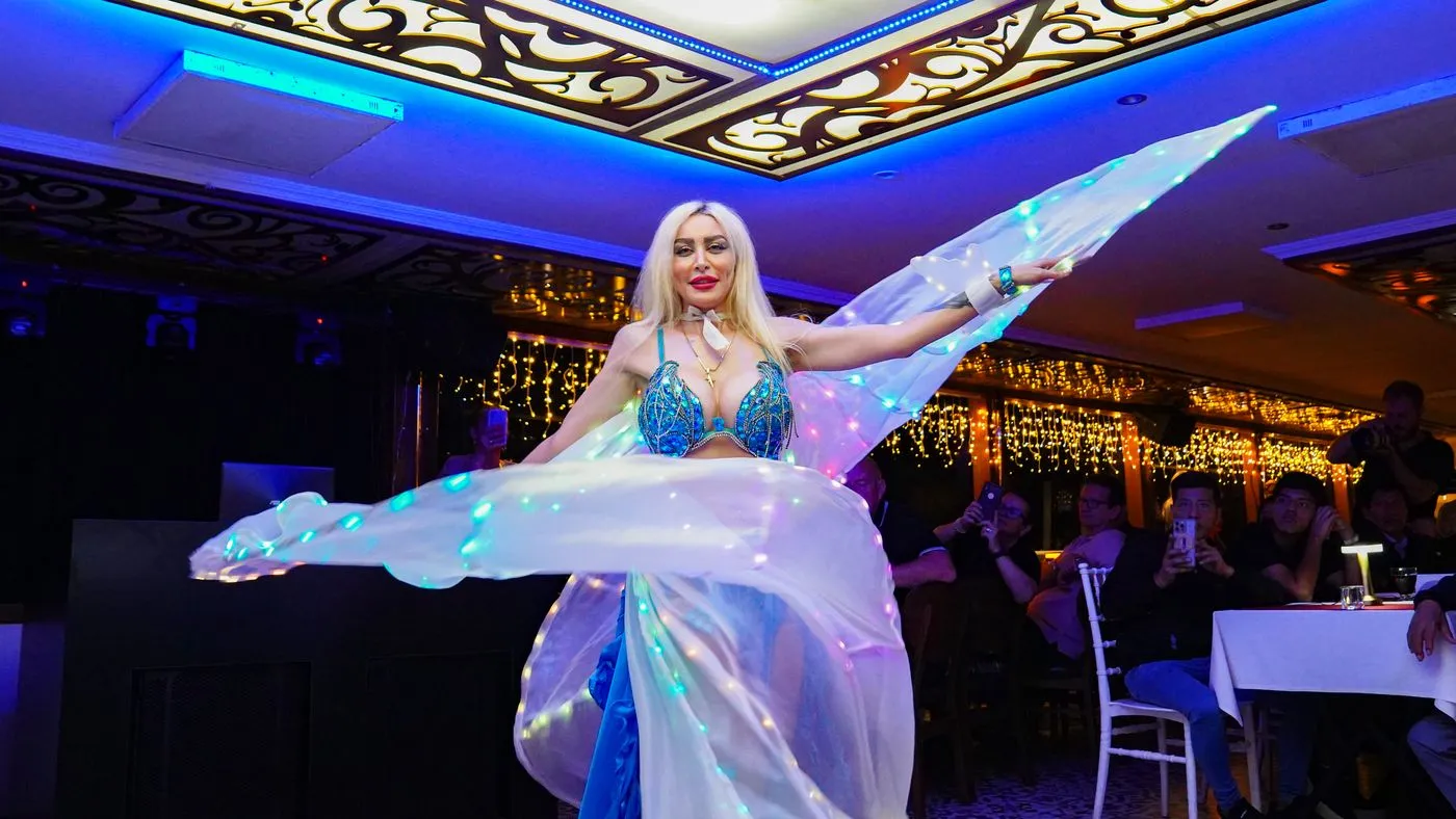 Belly dancer with illuminated veil wings in the salon
