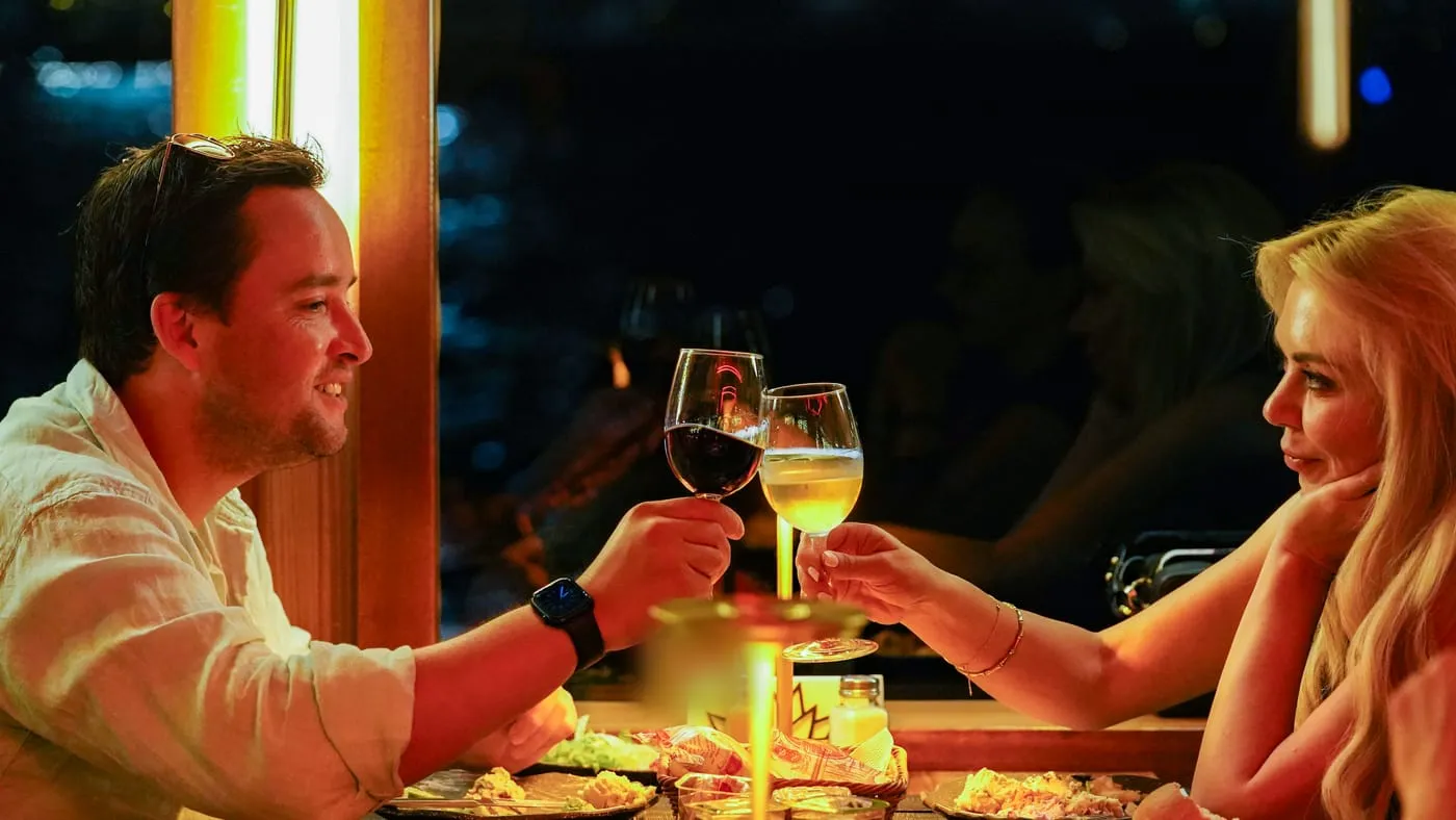 Two guests raising their glasses at a window table