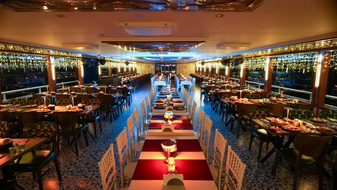 The dining salon at night: laid tables, string lights along the panoramic windows
