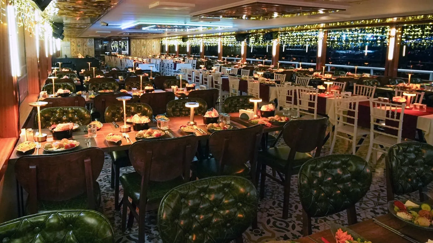 The dining salon at night, tables laid and string lights along the windows