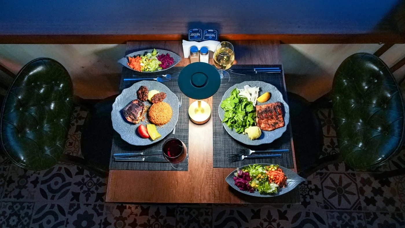 Two main courses on a table for two, seen from above: mixed grill and grilled salmon