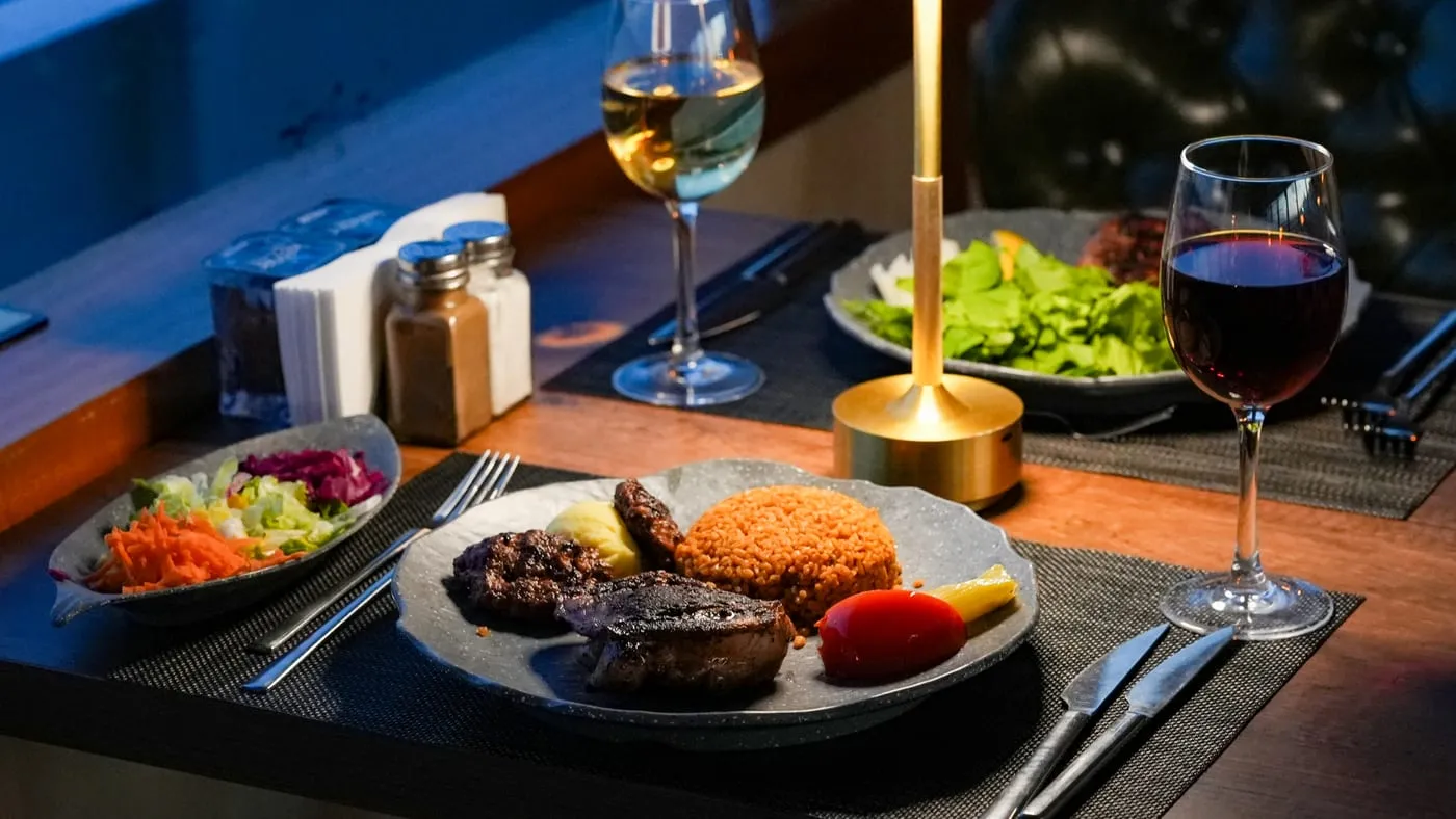 Köfte and grilled chicken with bulgur pilaf, salad and a glass of red wine