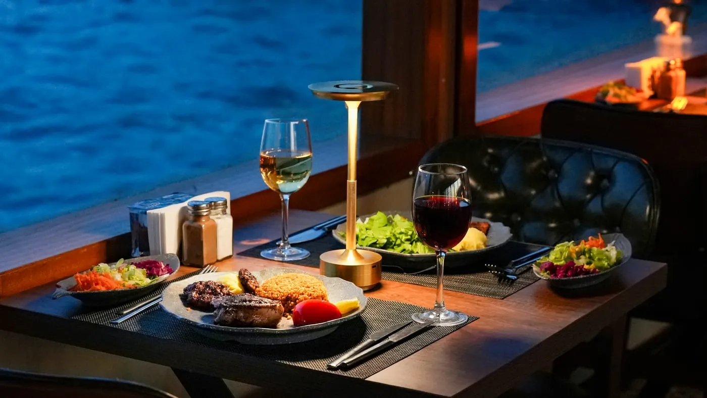 Mixed grill with bulgur pilaf, salads and two glasses of wine at a window table