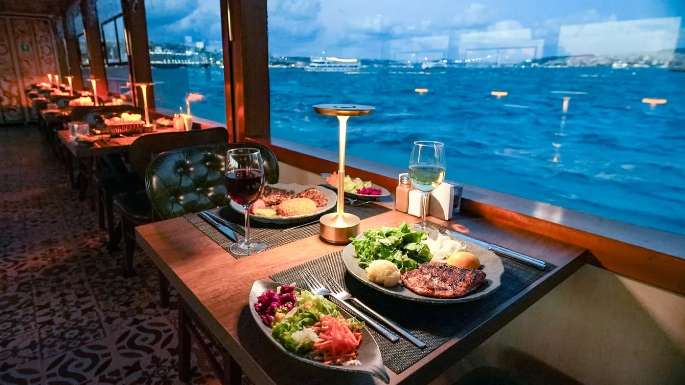 Window tables with dinner served and the Bosphorus and the city outside