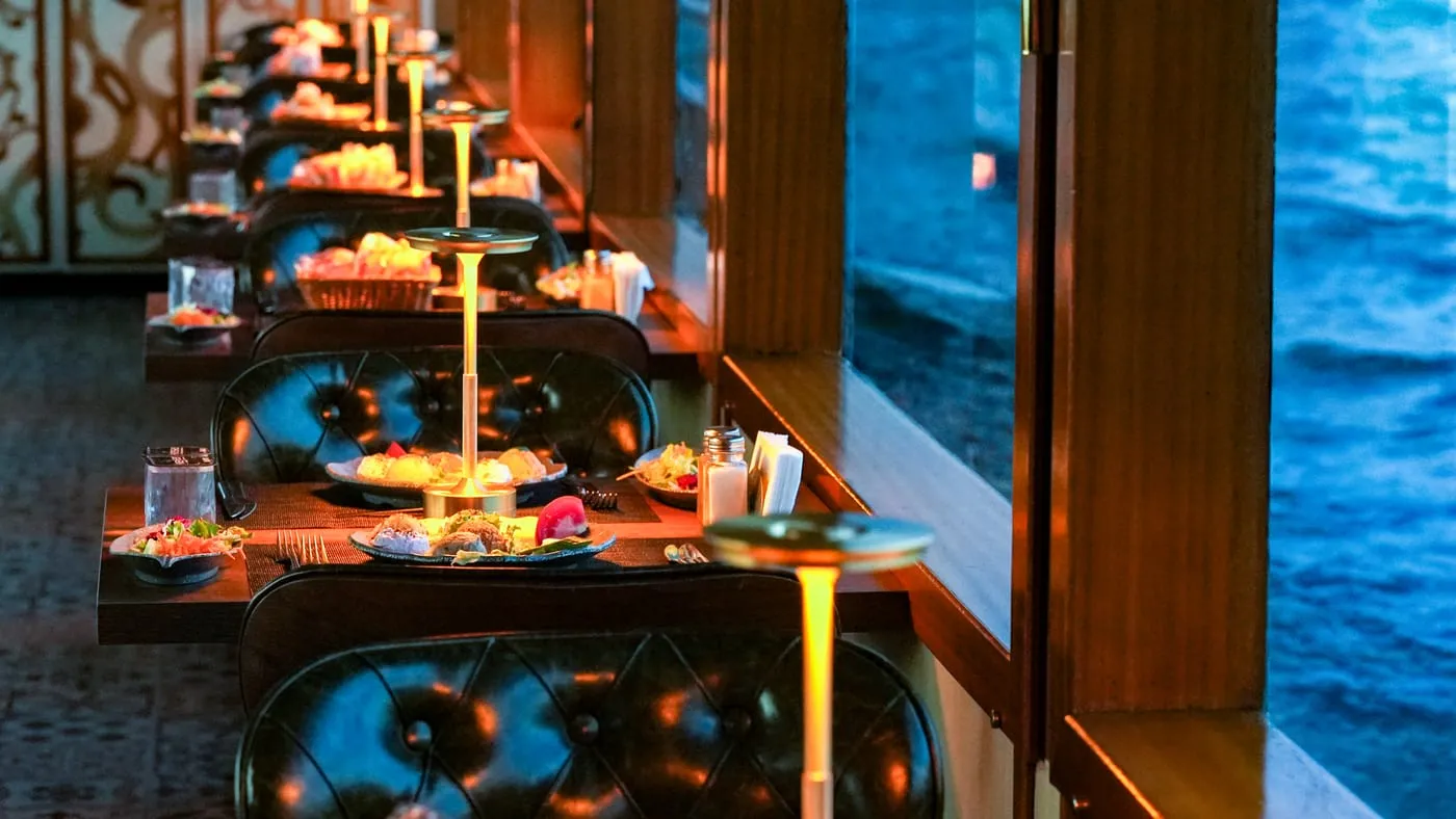 A row of window tables with their lamps lit, the Bosphorus outside