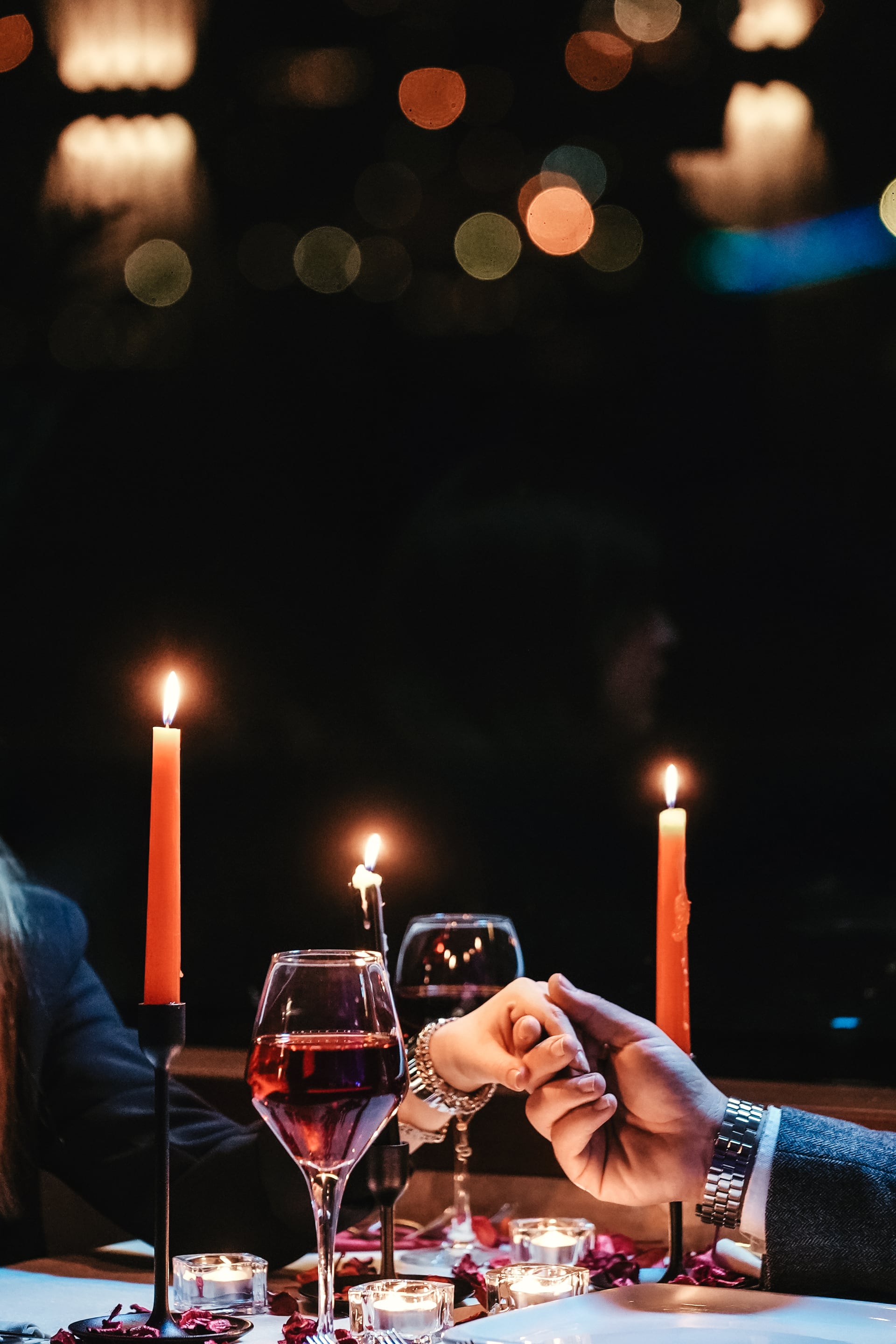 A couple raising glasses on the open deck with the illuminated Bosphorus Bridge behind them