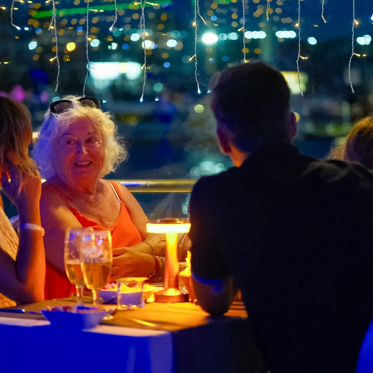 Guests at a window table with city lights behind