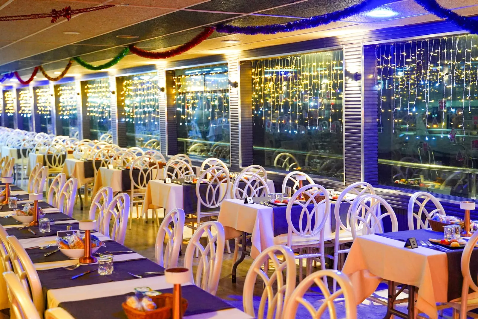 Dining salon with laid tables and fairy-light windows