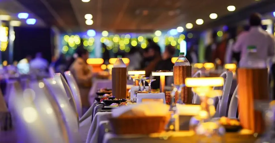 Laid dinner tables with copper table lamps on board